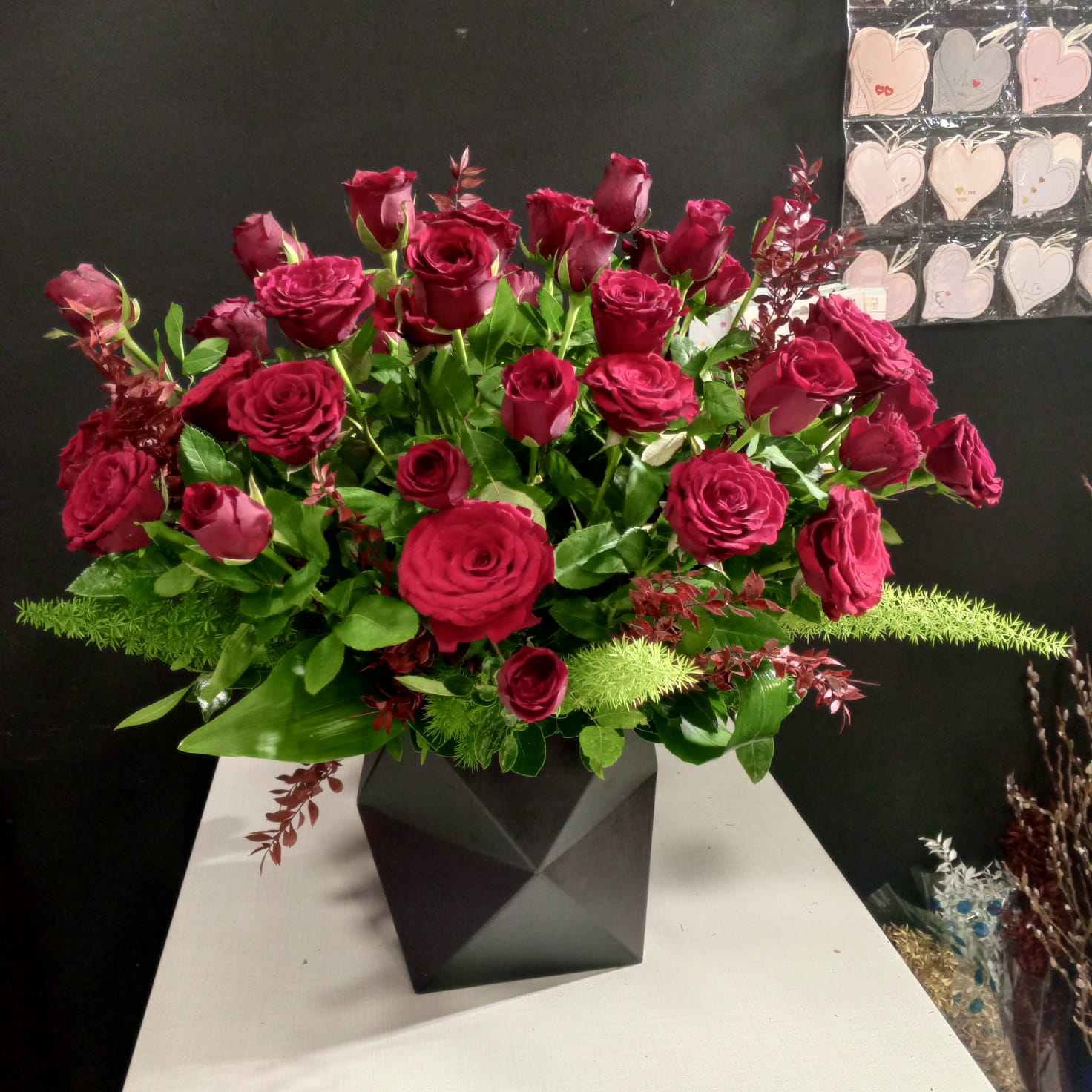 Luxurious red roses in geometric black vase with mixed greenery